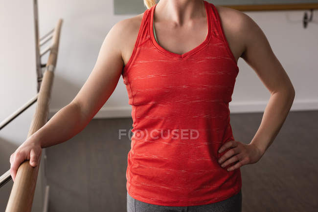 Mid section of young woman holding the barre at gym — Stock Photo