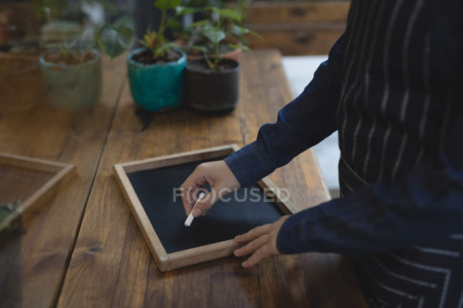 Barista escrevendo na ardósia com um giz no café — Fotografia de Stock