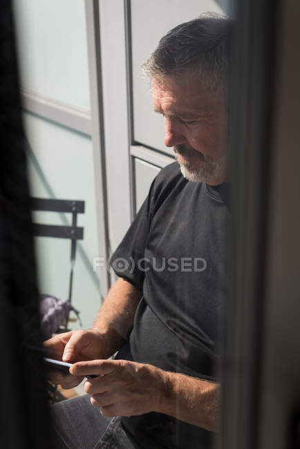 Hombre usando el teléfono móvil en la sala de estar en casa - foto de stock
