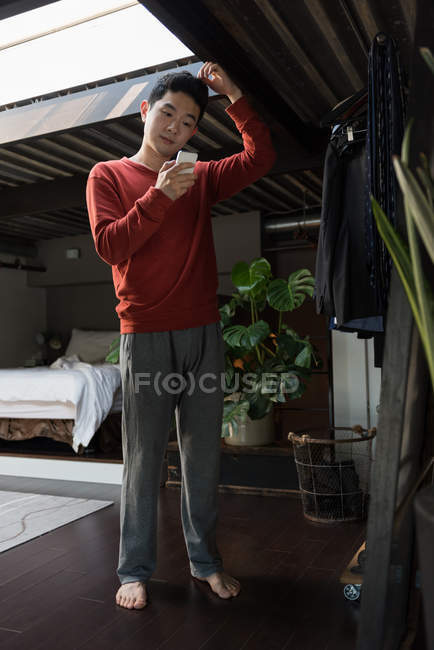 Молодой человек использует мобильный телефон дома — стоковое фото