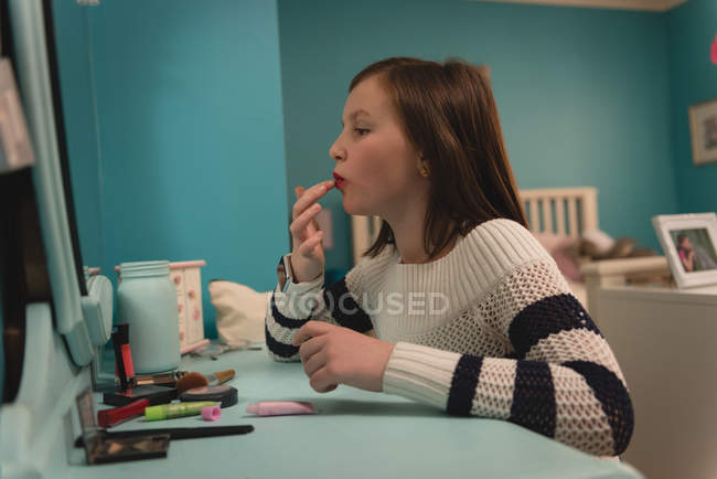Girl applying lipstick in bedroom at home — Stock Photo