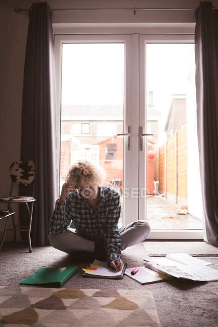 Jeune femme écrivant sur un bloc-notes à la maison — Photo de stock