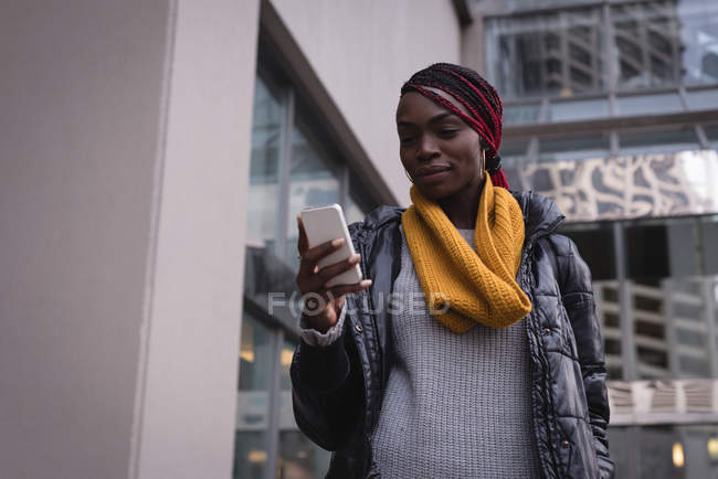 Young woman using mobile phone in city street — Stock Photo