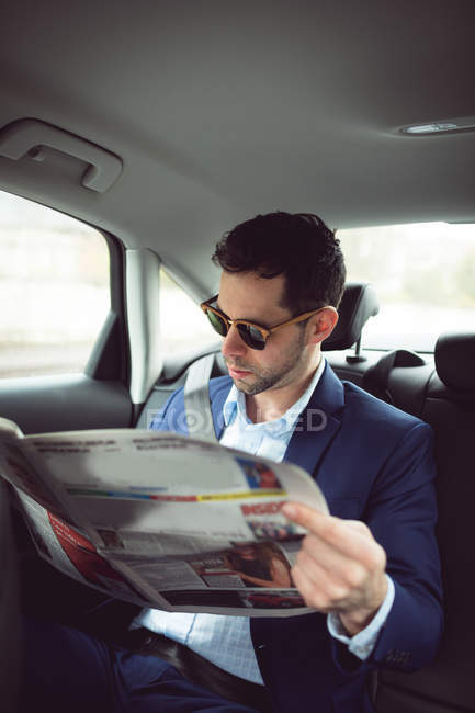 Inteligente hombre de negocios leyendo periódico en un coche - foto de stock