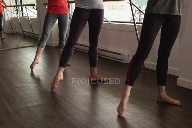 Low section of group of women practicing leg stretching at the gym — Stock Photo