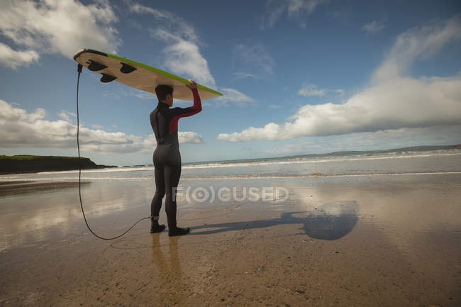 Серфер с доской для серфинга на голове в солнечный день — стоковое фото