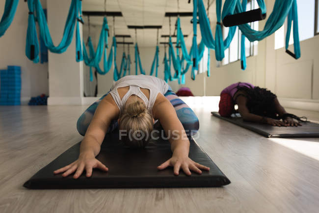 Two women performing yoga exercise in fitness studio — Stock Photo