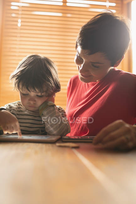 Mère enseignant à son fils sur tablette numérique à la maison — Photo de stock