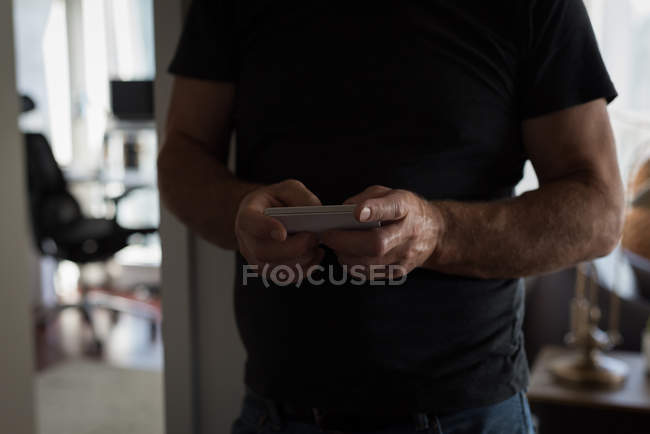 Seção média do homem usando telefone celular na sala de estar em casa — Fotografia de Stock