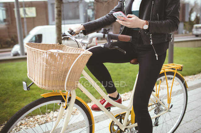 Низкая часть женщины на велосипеде с помощью мобильного телефона — стоковое фото