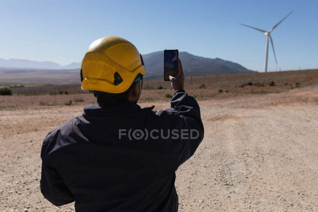 Инженер фотографирует ветряную мельницу на ветряной электростанции — стоковое фото