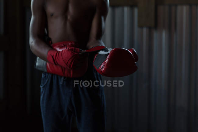 Partie médiane du boxeur masculin pratiquant la boxe dans un studio de fitness — Photo de stock