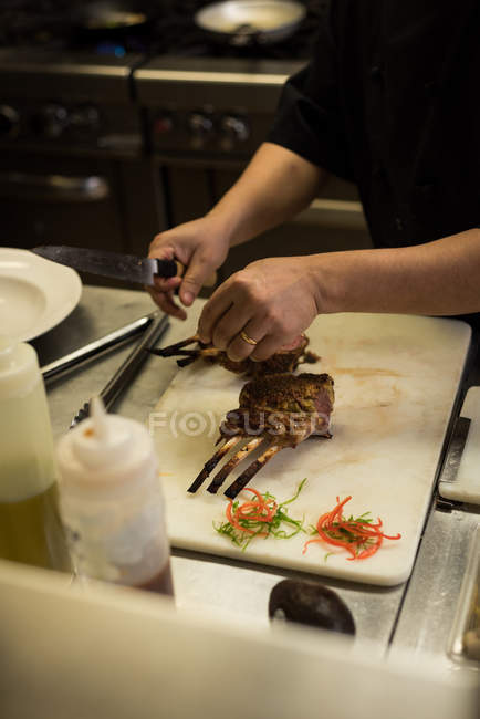 Section médiane du chef masculin préparant la viande dans la cuisine — Photo de stock