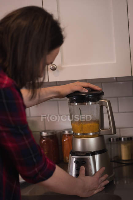 Woman using mixer grinder in kitchen at home — Stock Photo