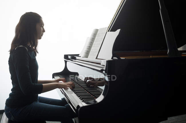 Vista laterale della studentessa che suona il pianoforte nella scuola di musica — Foto stock