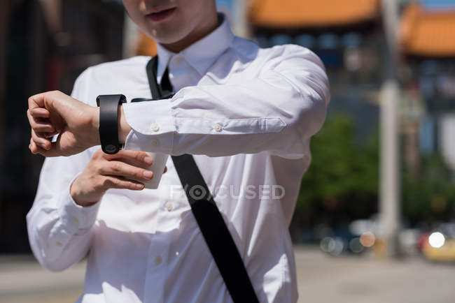 Средняя секция человека проверяет время во время прогулки по улице — стоковое фото