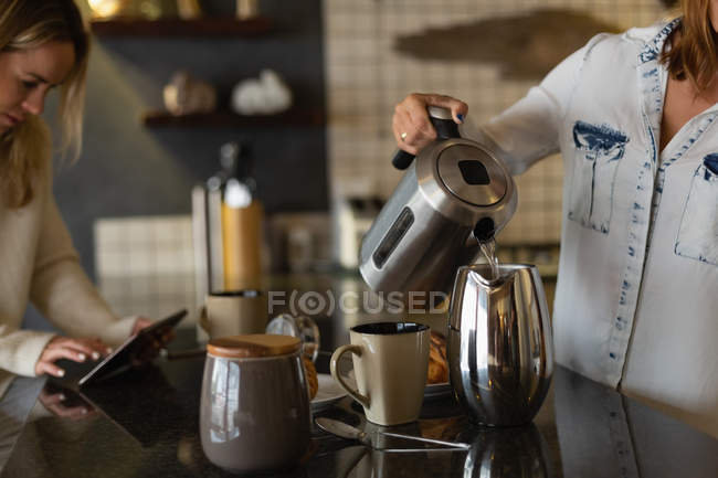 Лесбиянки готовят кофе на кухне дома — стоковое фото