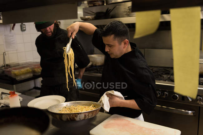Männlicher Koch bereitet in Küche im Restaurant Nudeln zu — Stockfoto