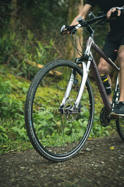 Low section of cyclist riding bicycle through lush forest — Stock Photo