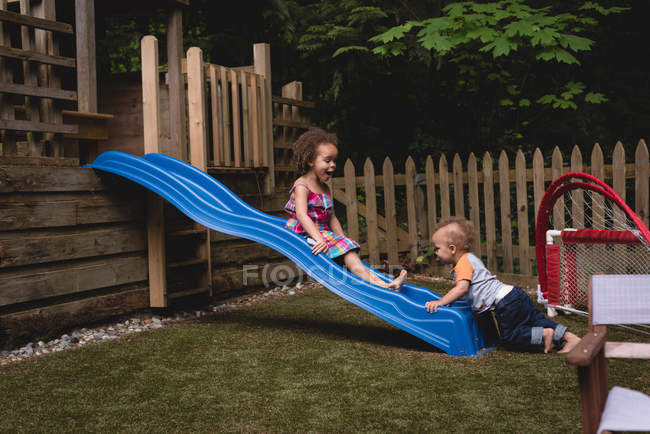 Frères et sœurs jouant dans le jardin par une journée ensoleillée — Photo de stock