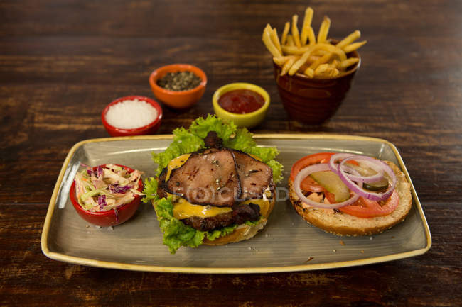 Hamburger di carne con patatine fritte servite sul tavolo di legno — Foto stock