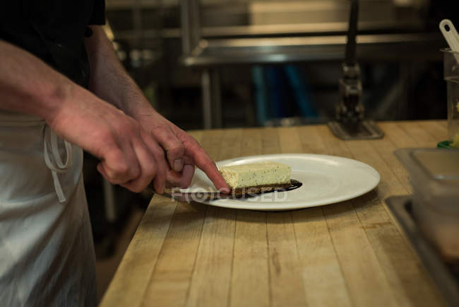 Seção intermediária de chef masculino servindo sobremesa em um prato — Fotografia de Stock