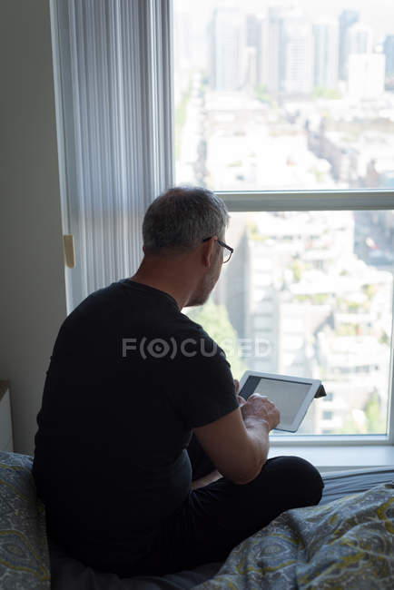 Вид ззаду людини, що використовує цифровий планшет у спальні вдома — стокове фото