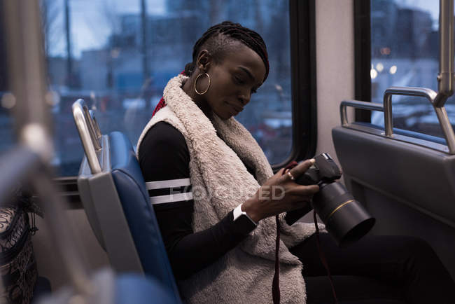 Donna che guarda la macchina fotografica digitale mentre viaggia in treno — Foto stock