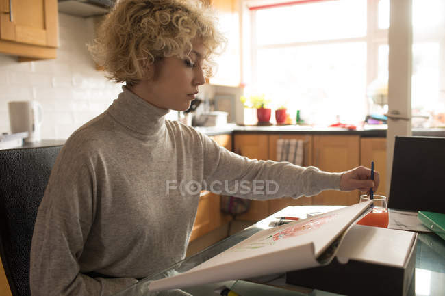Jovem mulher colorir um esboço em casa — Fotografia de Stock