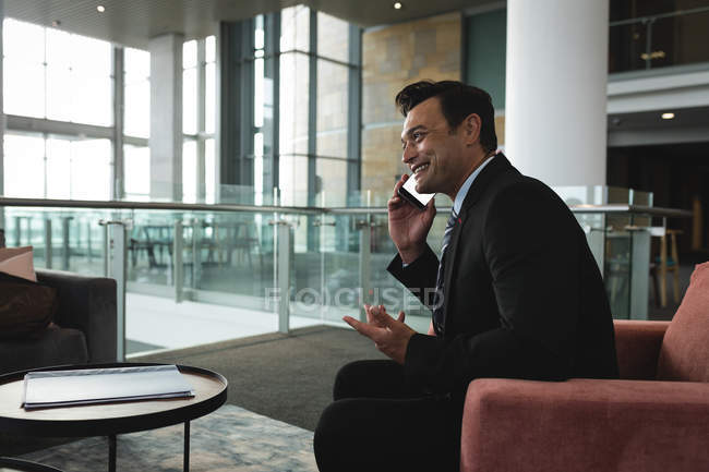 Un uomo d'affari sorridente che fa gesti mentre parla al telefono — Foto stock