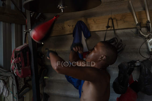 Boxeador masculino praticando boxe com saco de perfuração um estúdio de fitness — Fotografia de Stock
