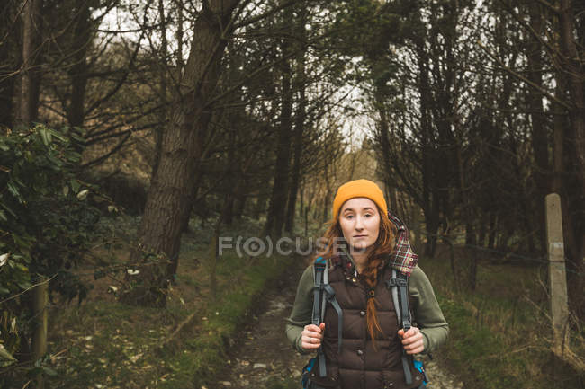 Vista frontal de una joven excursionista parada en el bosque - foto de stock