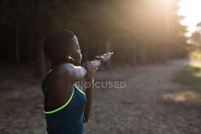 Female athlete doing stretching exercise in the forest — Stock Photo
