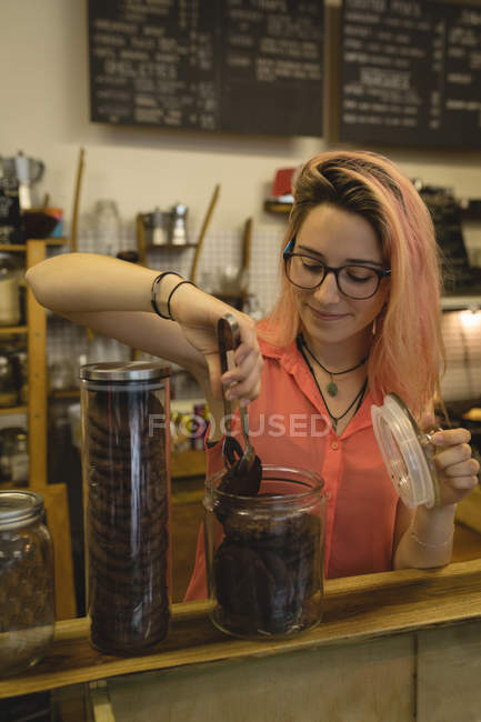 Jeune barista retirant un cookie d'un pot dans un café — Photo de stock