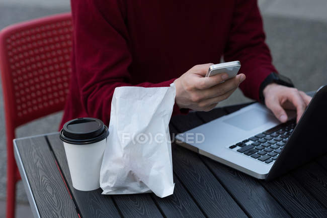 Середина людини, що використовує мобільний телефон у відкритому кафе — стокове фото