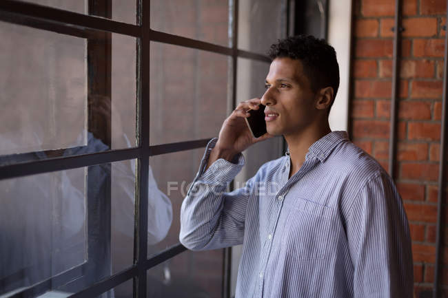 Мужчина разговаривает по мобильному телефону у окна дома — стоковое фото