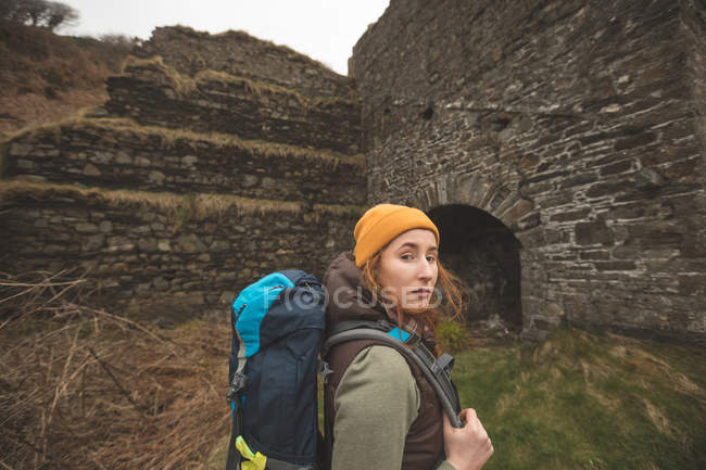 Retrato de hermosa excursionista femenina con mochila mirando a la cámara - foto de stock