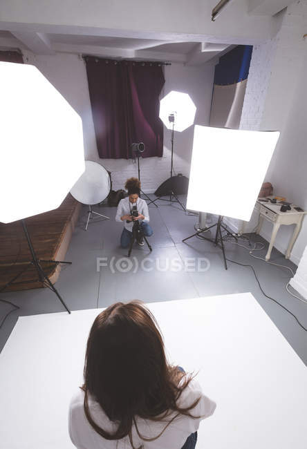 Photographe femelle en cliquant sur les photos du modèle en studio photo — Photo de stock