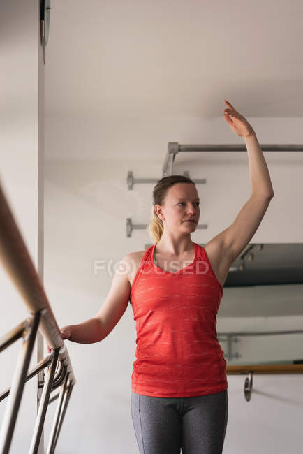 Junge Frau dehnt sich auf der Barre in der Turnhalle — Stockfoto