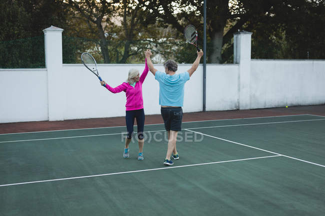 Feliz casal sênior torcendo no campo de ténis — Fotografia de Stock