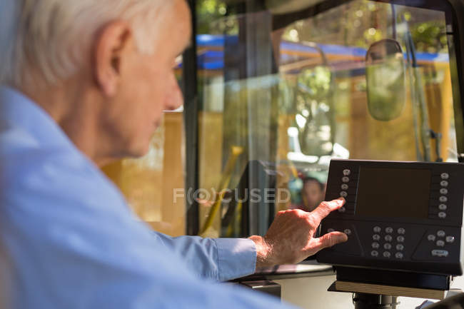 Senior driver operating machine in bus — Stock Photo