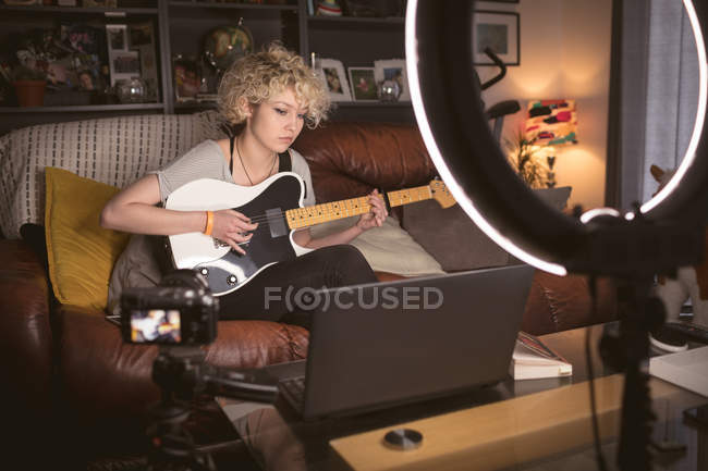 Blogueira feminina tocando guitarra na sala de estar em casa — Fotografia de Stock