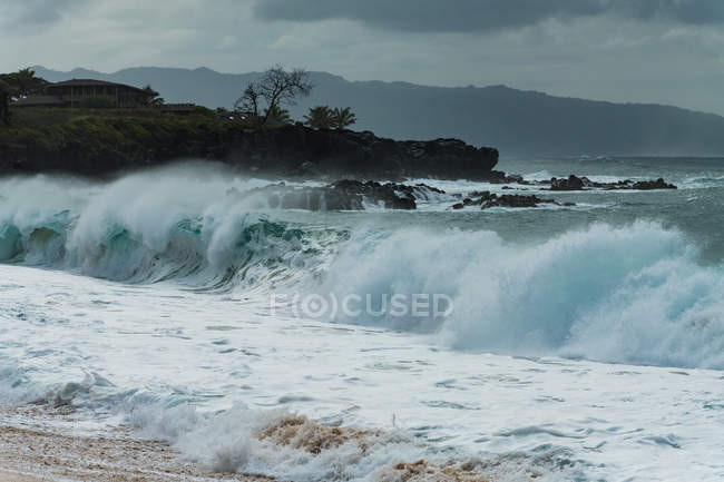 Welle des Meeres stürzt bei dunklem Wetter am Strand ab — Stockfoto