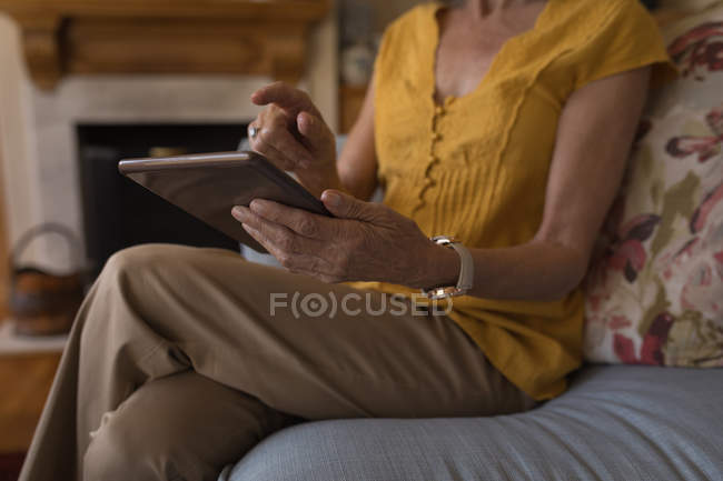 Seção média da mulher idosa usando tablet digital em casa — Fotografia de Stock