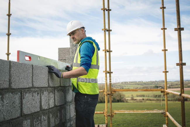 Ingénieur effectuant une vérification de niveau sur le mur sur le chantier de construction — Photo de stock