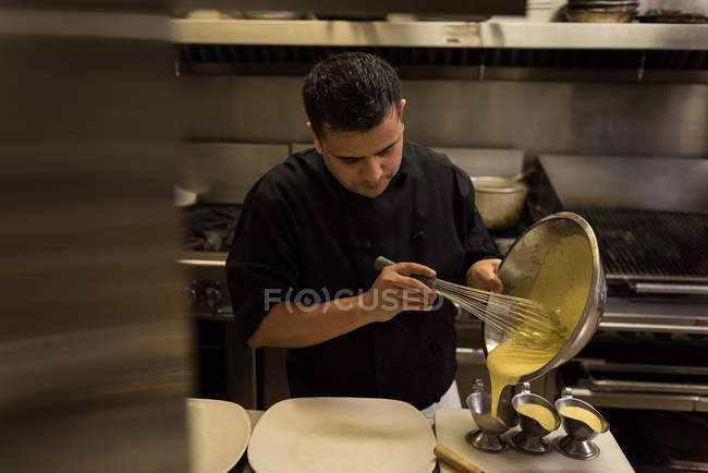 Мужской шеф-повар готовит еду на кухне в ресторане — стоковое фото