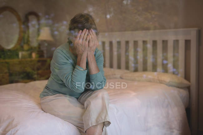 Preoccupata donna anziana seduta sul letto a casa — Foto stock