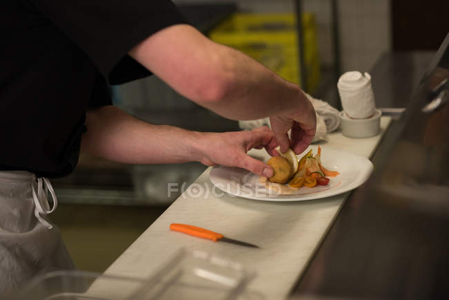 Chef macho sirviendo comida en un plato - foto de stock