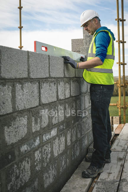 Ingegnere che fa un controllo di livello sul muro in cantiere — Foto stock