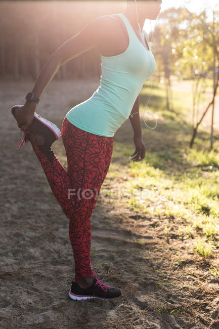 Женщина-атлет делает упражнения на ногах в лесу — стоковое фото